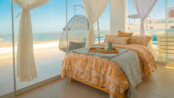 A bedroom with a bed, a hanging chair, and a view of the sea.
