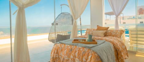 A bedroom with a bed, a hanging chair, and a view of the sea.