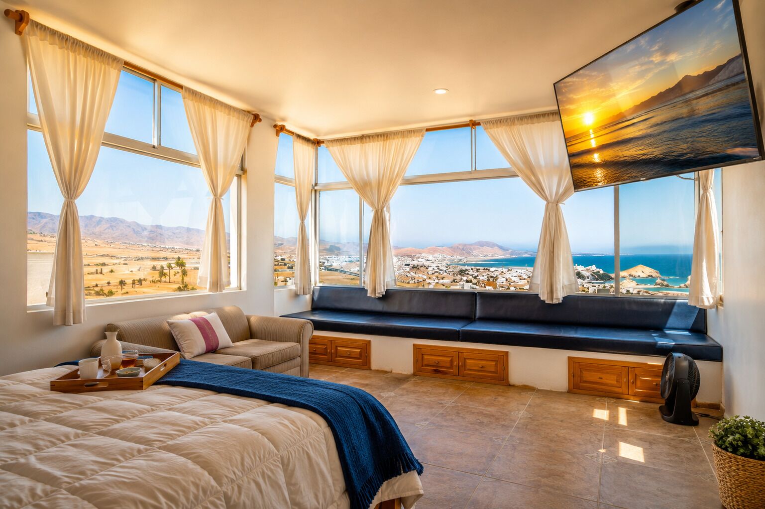 Un dormitorio con una cama grande, una zona de estar con vistas y un ventanal que da a un paisaje.