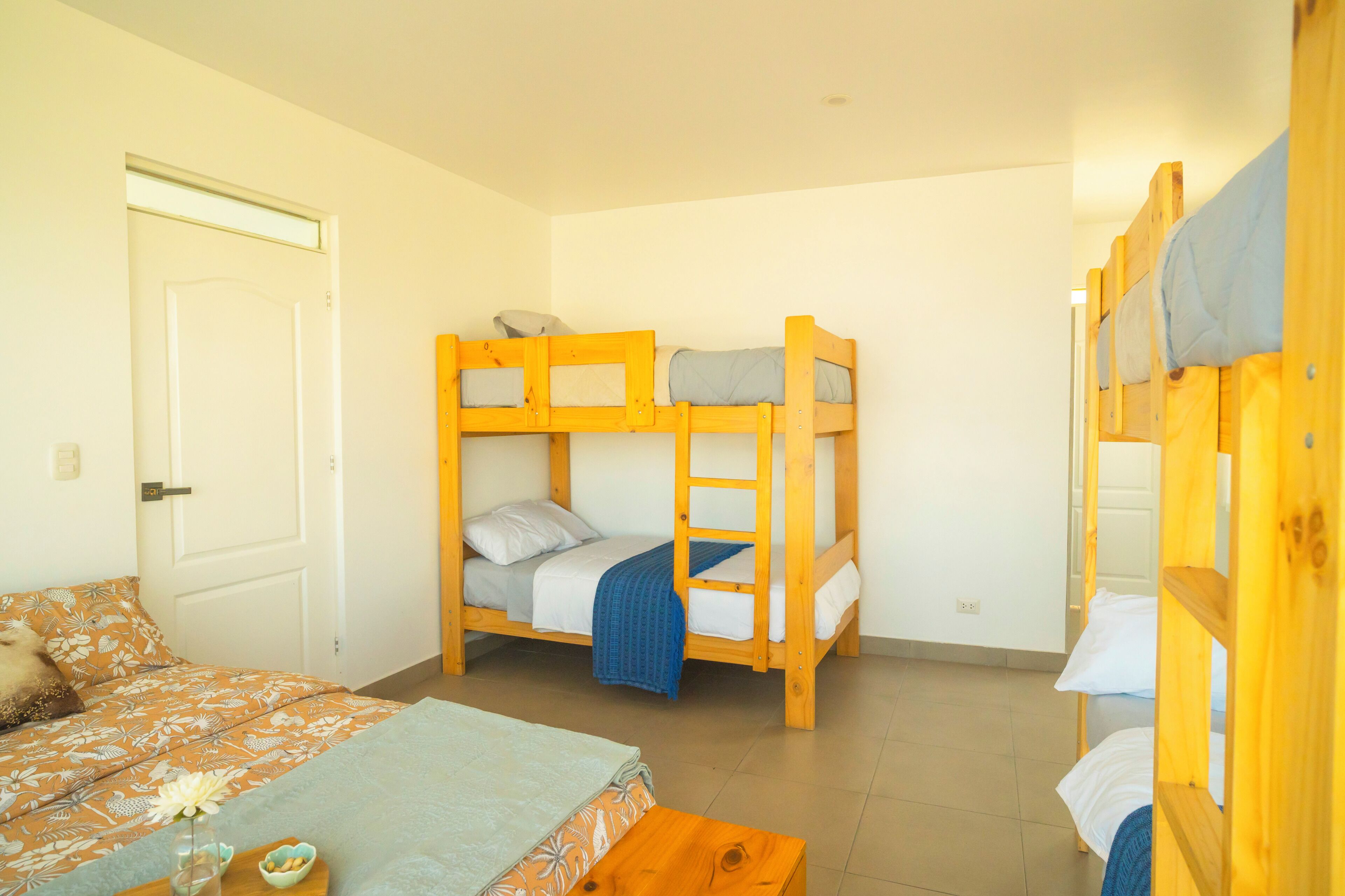 Una habitación con literas, una puerta y una cama con colcha estampada.