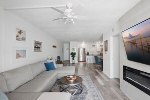 A modern living room with a sofa, coffee table, and a TV mounted on the wall. - Brightwater Beach Condo | Bay Views & Beach Access (St. Petersburg)