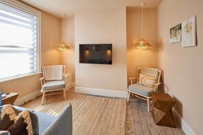Ein gemütliches Zimmer mit zwei Holzstühlen, einem Flachbildfernseher und zwei Pendelleuchten.