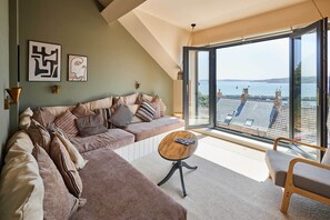 A modern living room with a large window, a sofa, a coffee table, and a chair. - Host & Stay | Casa Formentera (Scarborough)