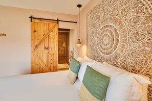 A bedroom with a wooden door, a large patterned tapestry, and a bed with pillows. - Host & Stay | Casa Formentera (Scarborough)