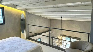Ein Schlafzimmer mit einem großen Bett, einem Sessel, einem Balkon mit Blick und einer Chandelier.