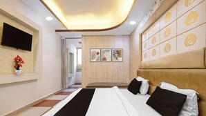 Ein Hotelzimmer mit einem Bett, einem an der Wand befestigten Flachbildfernseher und einem Fenster mit Vorhängen.