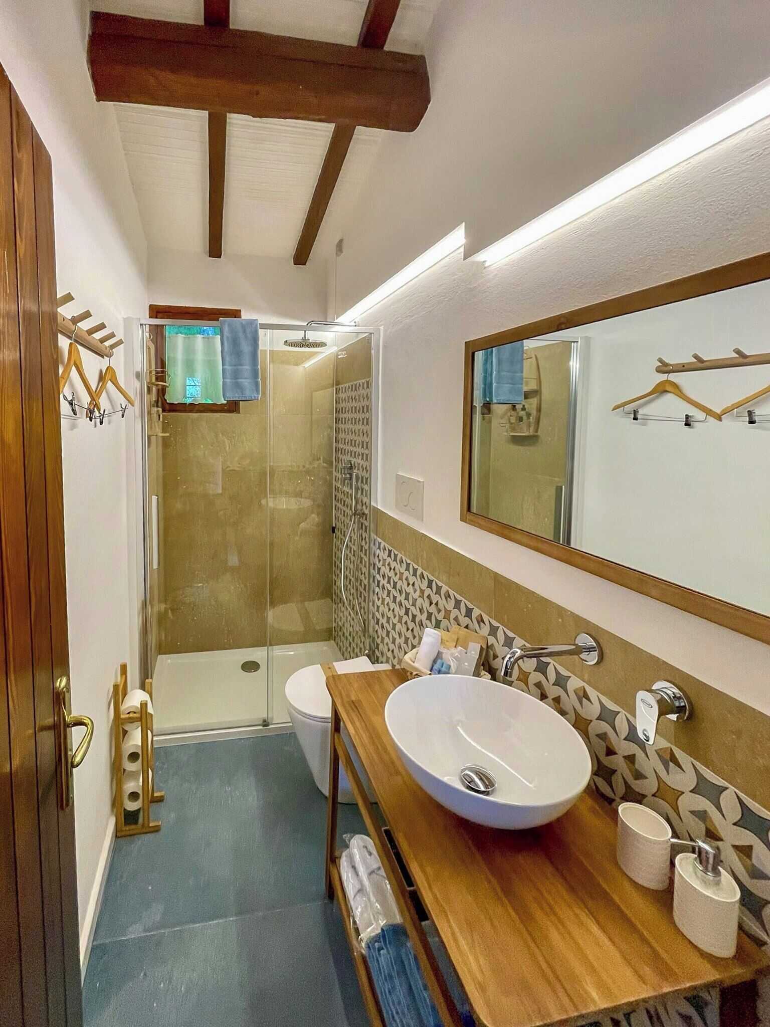 A modern bathroom with a glass shower, a wooden vanity, and a large mirror.