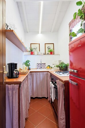 A compact kitchen with a red refrigerator, a coffee maker, and various kitchen utensils. - Stone cottage with view of Gubbio and shared pool (Gubbio)