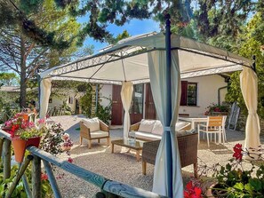 Un espacio de estar al aire libre techado con mobiliario de mimbre y una pérgola.