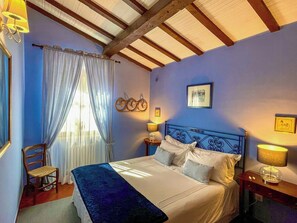 A bedroom with a bed, a chair, a nightstand, and a window with curtains. - Stone cottage with view of Gubbio and shared pool (Gubbio)