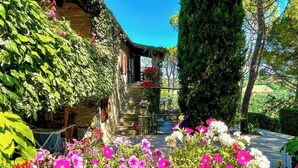 A stone building with a staircase leading to a door, surrounded by lush greenery and flowering plants. - Stone cottage with view of Gubbio and shared pool (Gubbio)