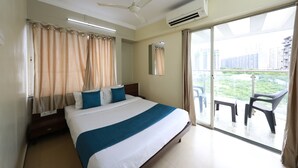 A hotel room with a bed, a ceiling fan, an air conditioning unit, and a balcony with chairs. - Hotel Alt Acco close to Kharadi (Pune)