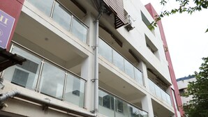 A multi-story building with a parking garage below. - Hotel Alt Acco close to Kharadi (Pune)