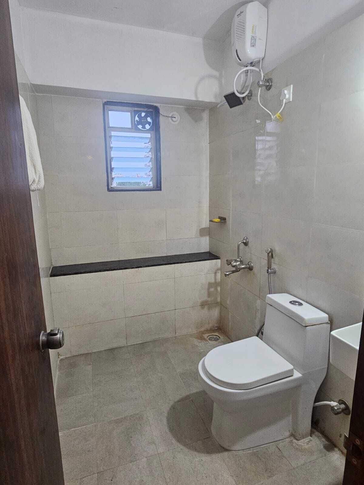 A bathroom with a toilet, a shower, and a window.