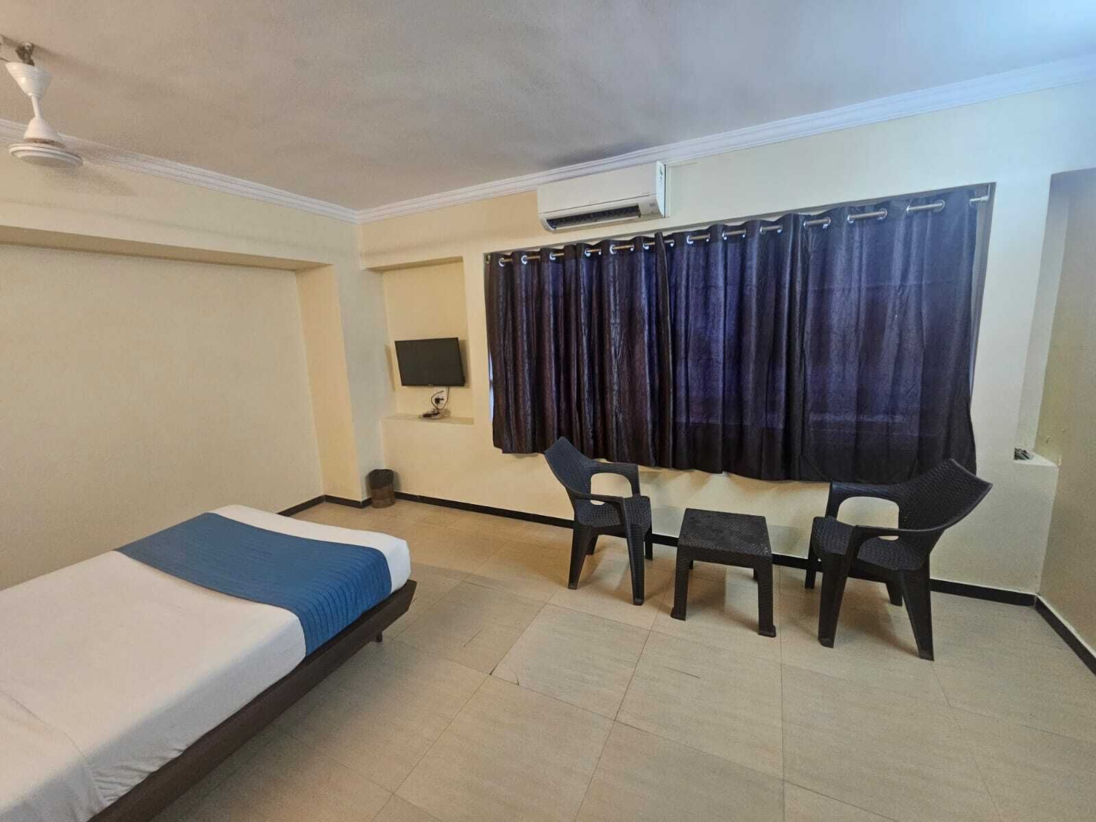 Ein Hotelzimmer mit Bett, Schreibtisch, Stuhl, Fernseher und Klimaanlage.