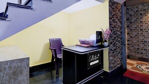 A reception desk with a Canon printer, a chair, and a vase with flowers. - Collection O Shyam Bazar Metro Station (Kolkata)