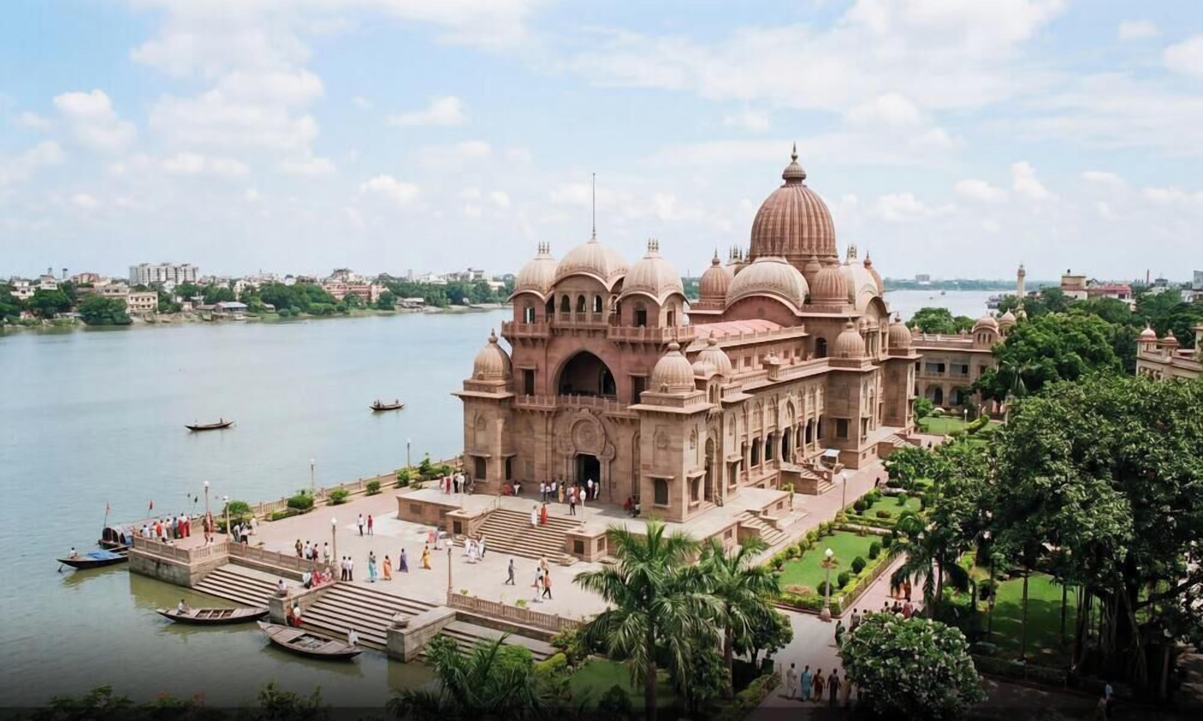 A large, historic building with multiple domes and a central dome, situated by a body of water with boats.