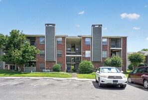 Un edifici d'apartaments de diverses plantes amb un aparcament al davant.