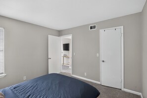 Ein Schlafzimmer mit einem Bett, zwei Türen und einem Fernseher auf einem Schrank.