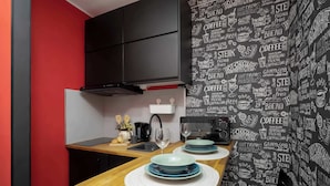 A modern kitchen with a wooden countertop, black cabinets, and a blackboard wall with food-related drawings. - Unique Studio for 2 Persons | Pet Friendly (Warszawa)