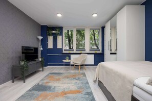 Ein modernes Schlafzimmer mit Bett, Schreibtisch und Fernseher.