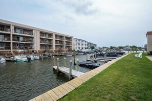 Un port esportiu amb embarcacions amarrades, un moll de fusta i un edifici de diversos pisos amb balcons.