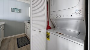 Ein Waschraum mit einer weißen Waschmaschine, einem Trockner und einem Schild mit der Aufschrift 'BEACH HOUSE'.