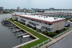 Ein Hotel direkt am Wasser mit mehreren Balkonen, einer Bootsanlegestelle und einer Stadtkulisse im Hintergrund.
