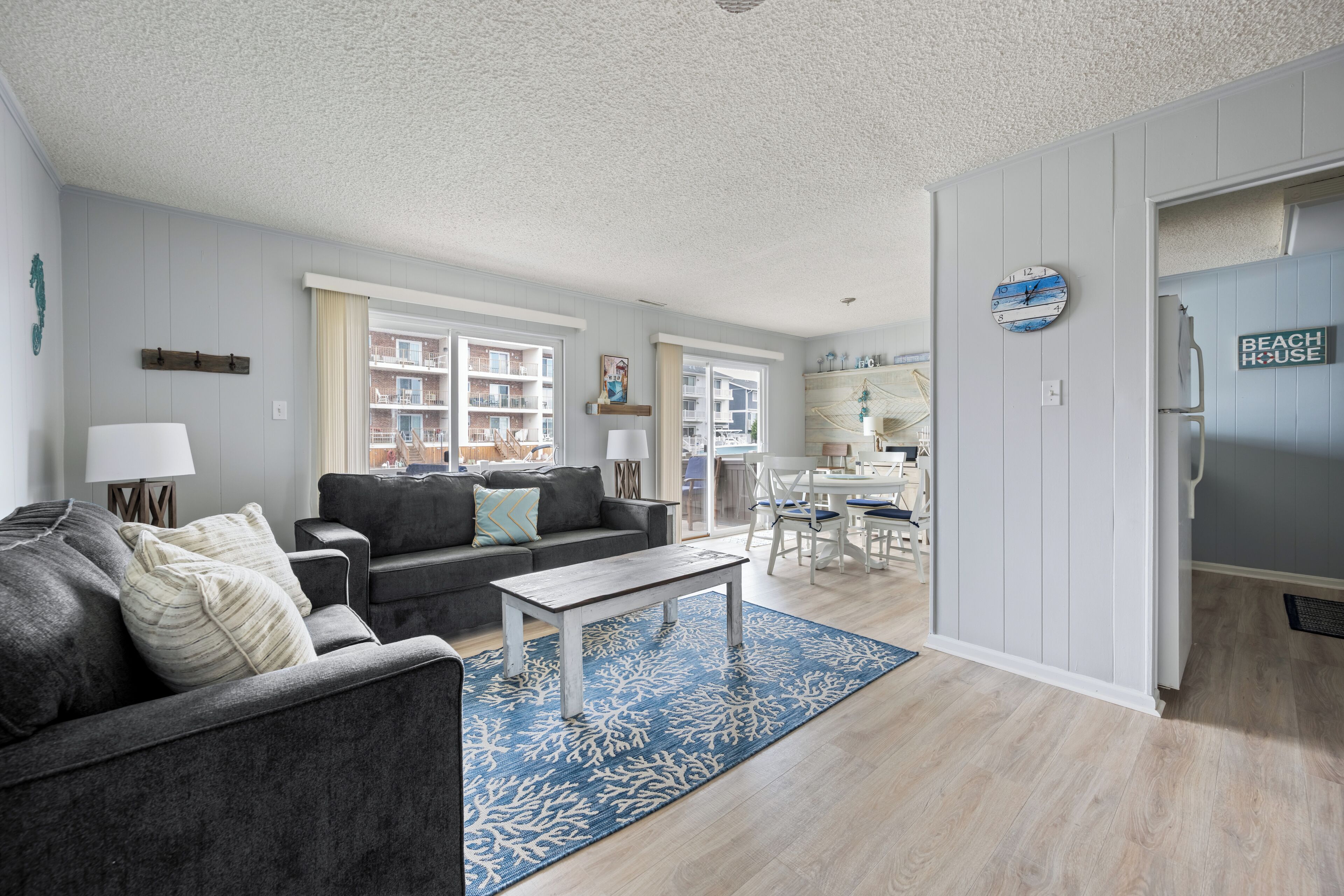 A modern living room with a grey sofa, a coffee table, and a blue patterned rug.