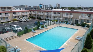 Ein Swimmingpool mit Liegestühlen und einem Zaun, umgeben von mehrstöckigen Gebäuden.