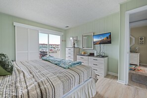 A bedroom with a bed, a dresser, a television, and a view of the outside. - Relax and Unwind on the Bay in North Ocean City (Ocean City)