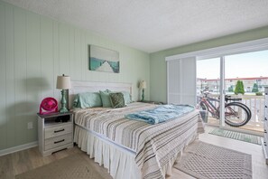 Ein Schlafzimmer mit einem Bett, Nachttischlampen, einem Nachttisch, einem Fenster mit Blick auf Fahrräder und einem Bild an der Wand.