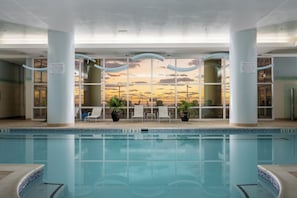 An indoor swimming pool with a sunset view, lounge chairs, and potted plants. - Three bedroom oceanfront condo in the luxurious Gateway Grand! (Ocean City)