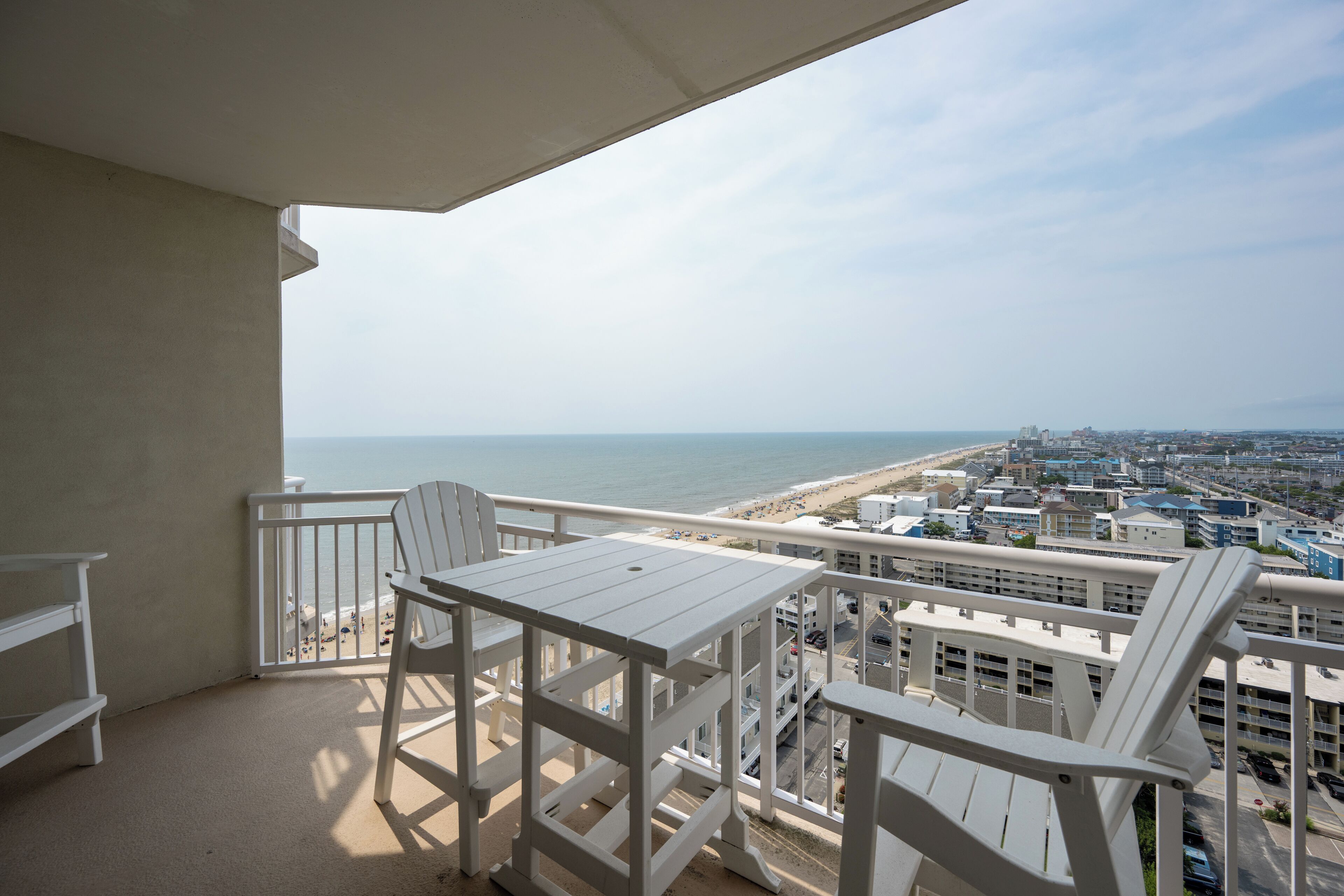 A balcony with a view of the beach and cityscape.