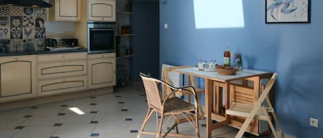 A kitchen with a dining table and chairs, a stove, and cabinets.