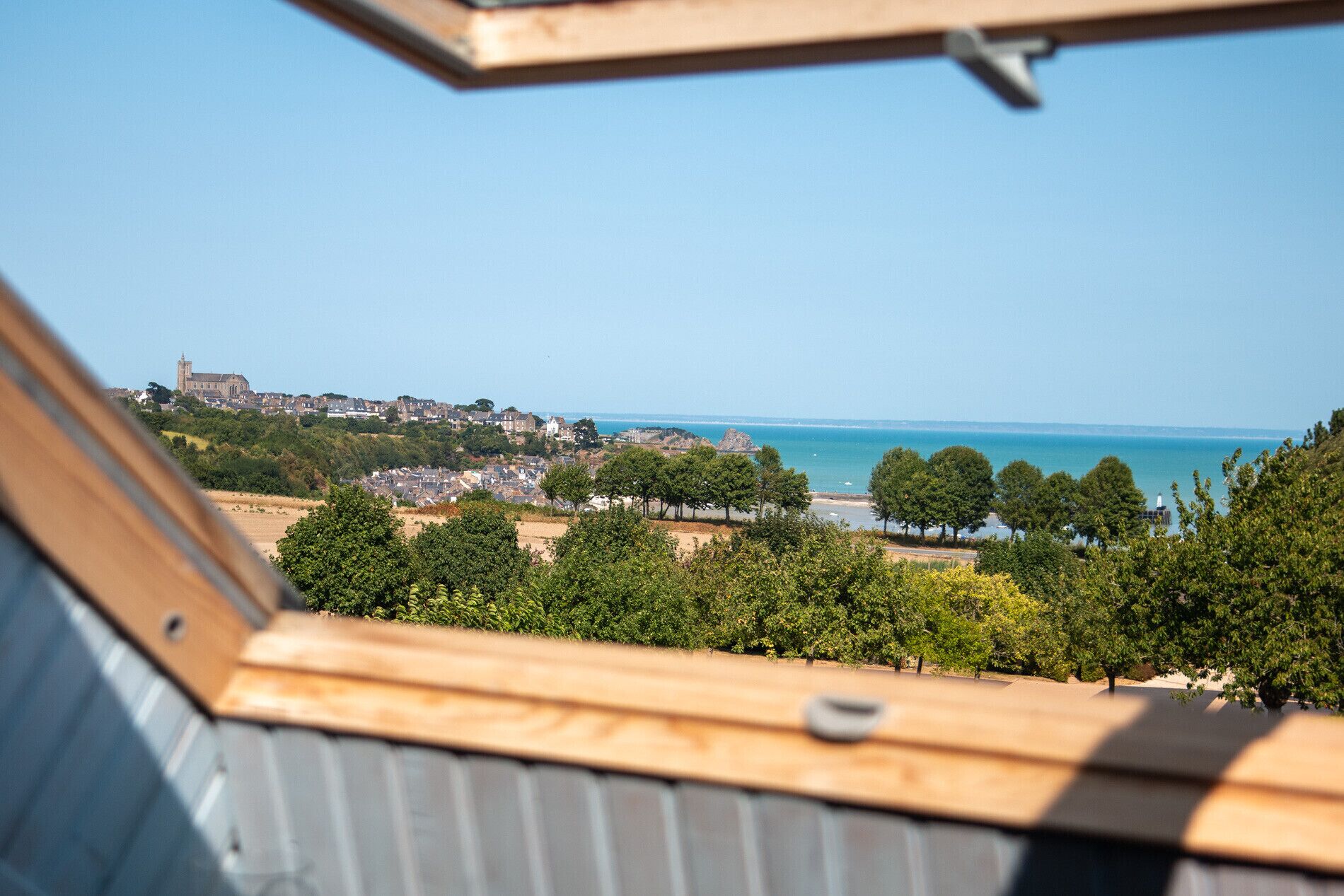 Uitzicht op de kust vanaf een balkon, met heldere lucht, een strand en een gebouw in de verte.