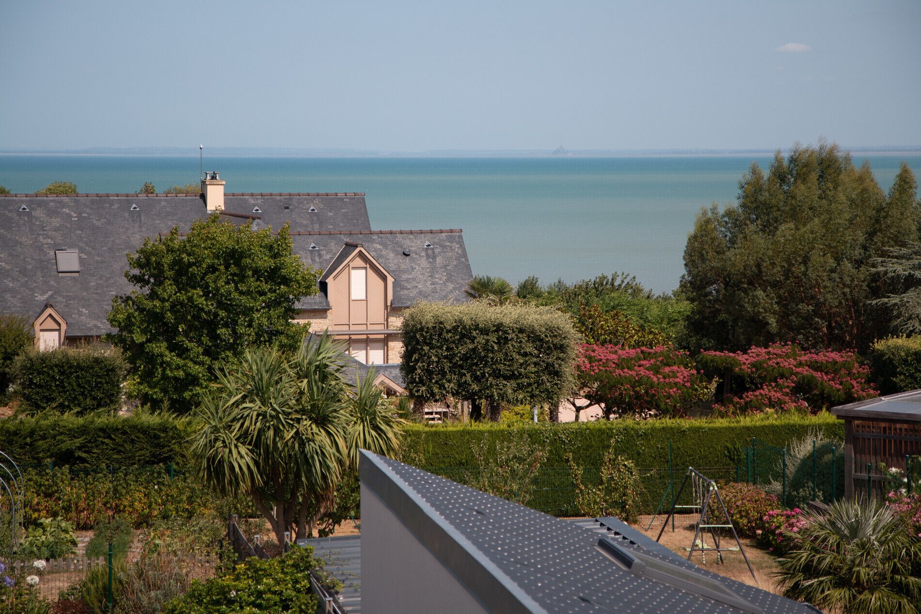 A residential area with houses, a garden, and a view of the sea.