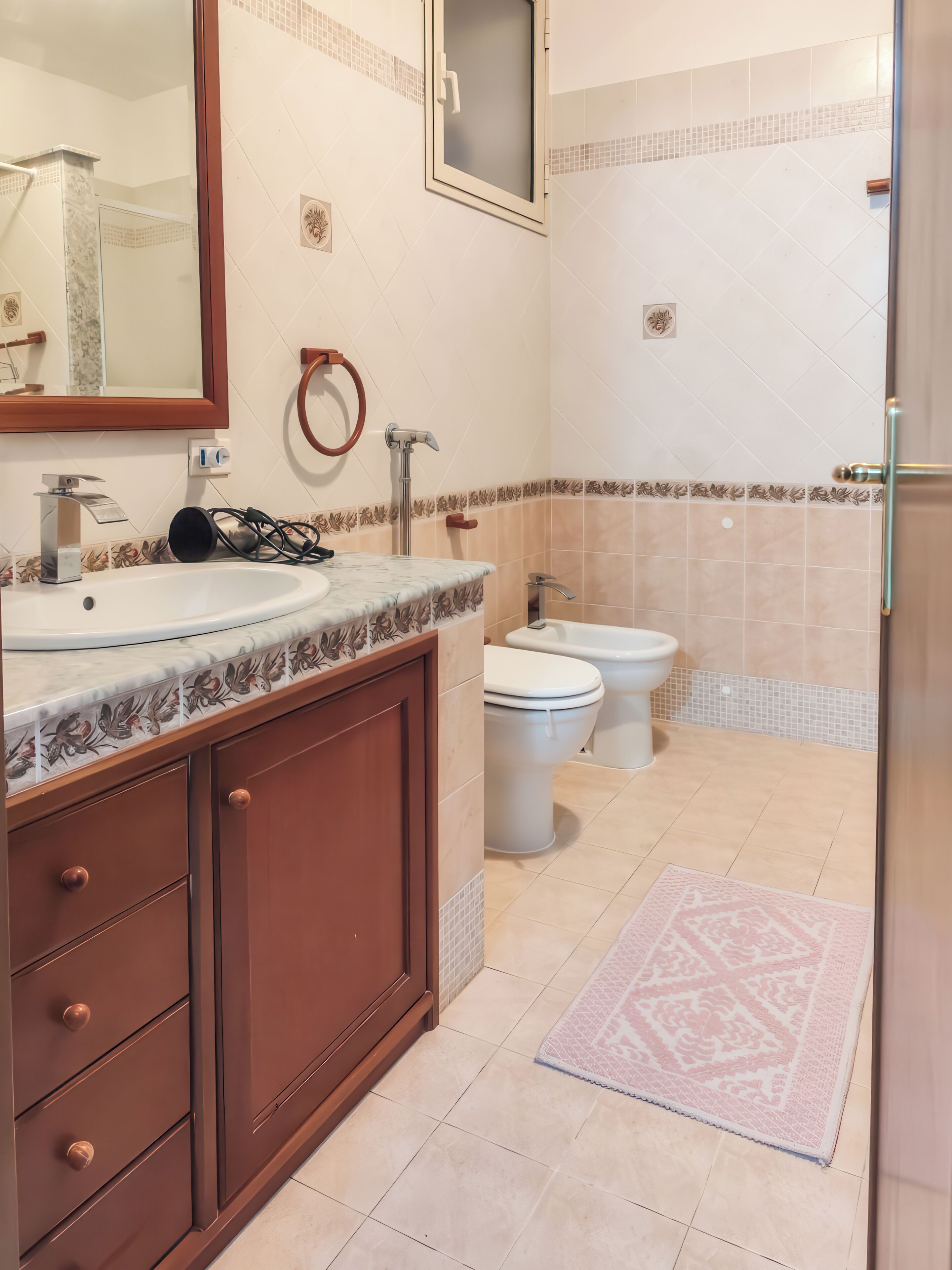 Ein Badezimmer mit Waschbecken, Spiegel, Toilette und Duschbereich.
