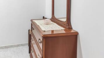 A wooden dresser with a mirror and drawers against a white wall.