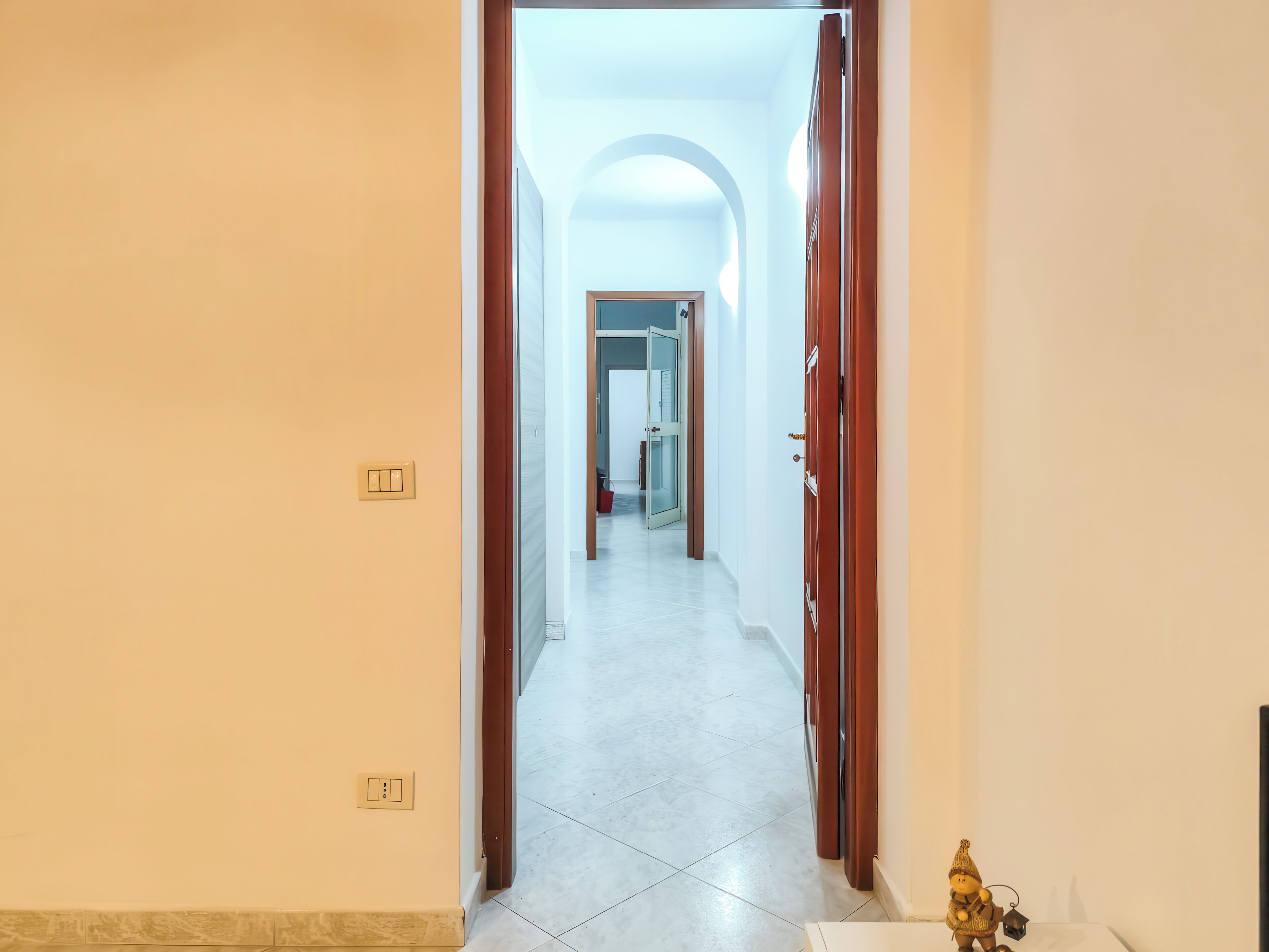 Un pasillo con un interruptor de luz y una puerta que da a otra habitación.