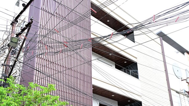 Un hotel con fachada vertical, un letrero y una entrada protegida por una reja.