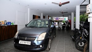 Un coche aparcado en una habitación con ventilador de techo, una motocicleta y un cartel en la pared.