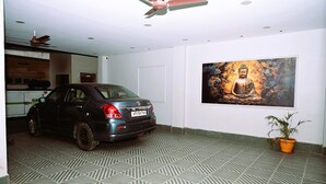 Un coche aparcado en una habitación con suelo estampado, un ventilador de techo y un cuadro en la pared.