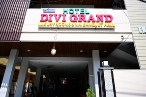 Une enseigne d’hôtel portant le nom « DIVI GRAND » et indiquant « CHAMBRES DE LUXE ET MINI-BAR ».