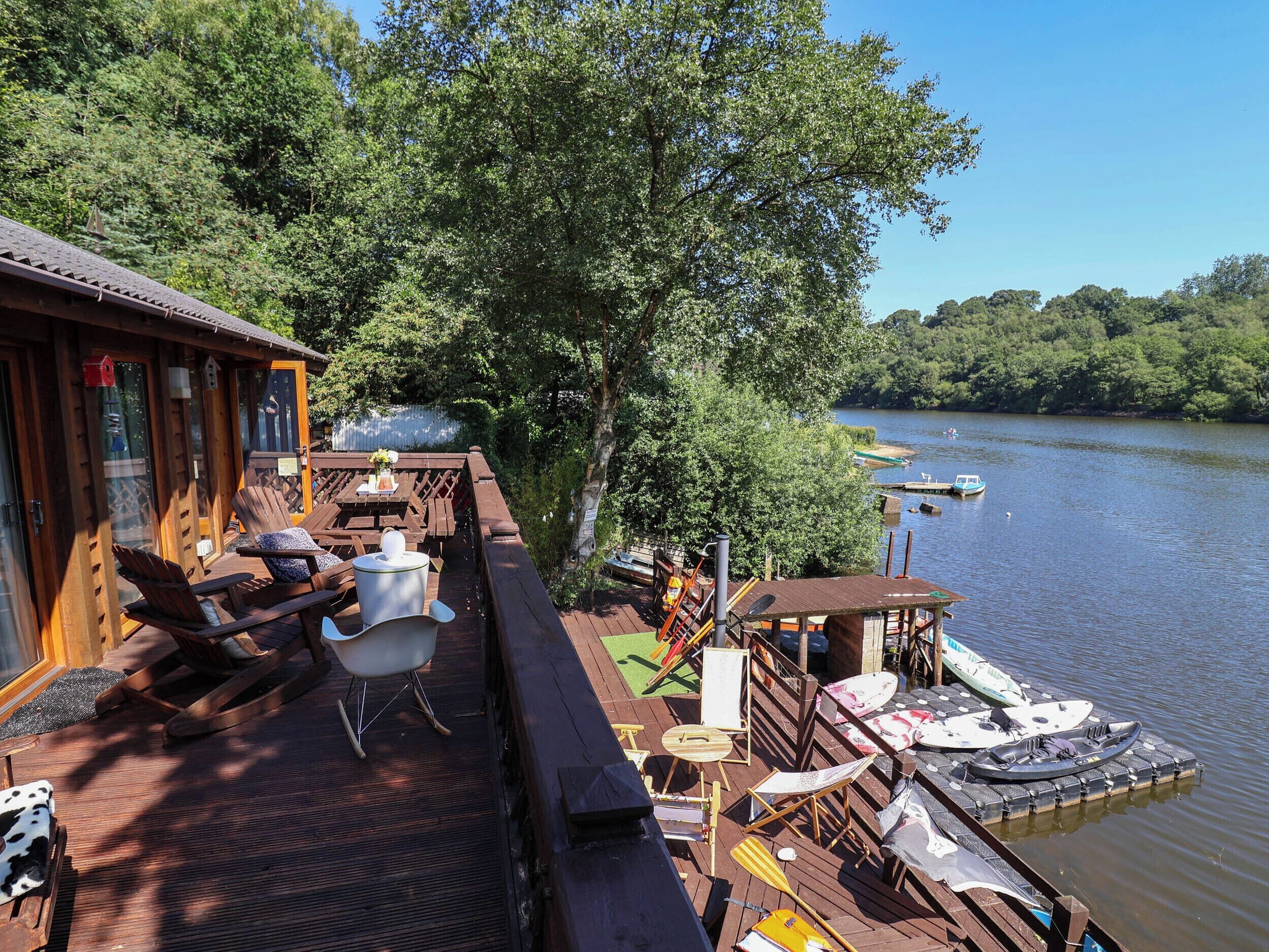 A wooden deck with outdoor seating and a view of a calm river.