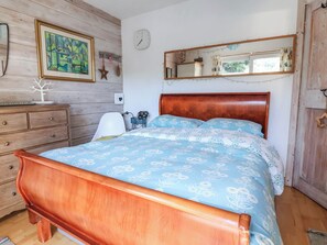 A bedroom with a wooden bed, a dresser, a mirror, and a wall clock. - Cool Cabin (Leek)