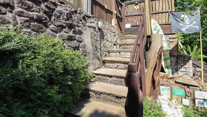A stone wall with a wooden fence, a staircase, and a flag with a skull and crossbones. - Cool Cabin (Leek)
