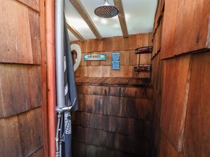 A narrow hallway with wooden walls and a ceiling fan. There is a sign on the wall that reads 'Surf Boards.' - Cool Cabin (Leek)