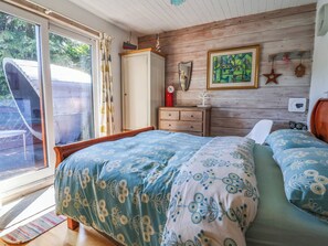 A bedroom with a bed, a dresser, a mirror, and a window with curtains. - Cool Cabin (Leek)