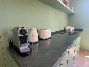 Eine Küchenarbeitsplatte mit Kaffeemaschine, zwei Wasserkochern und einem Toaster.